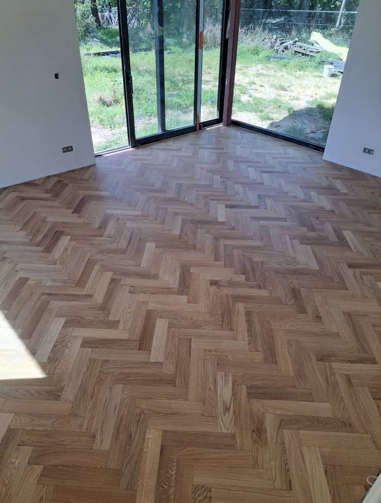 Freshly installed oak herringbone parquet in a new build room